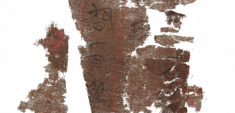 Torn pieces of brown cloth with faded black calligraphy. 